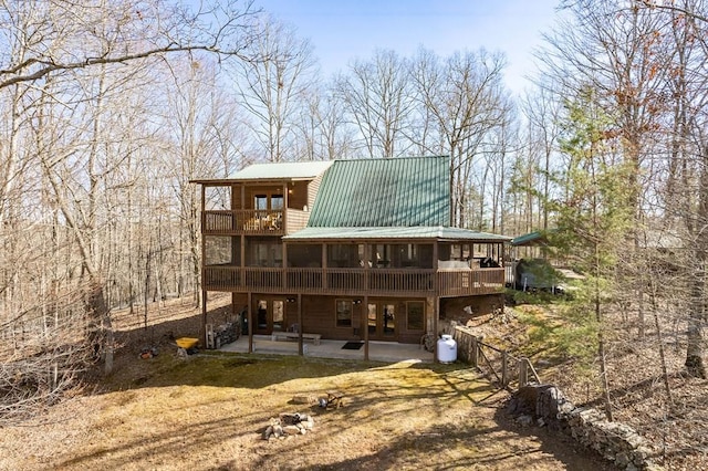 rear view of property featuring a patio area, metal roof, and a balcony