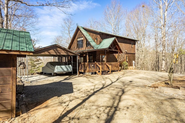 back of property featuring a carport, metal roof, and driveway