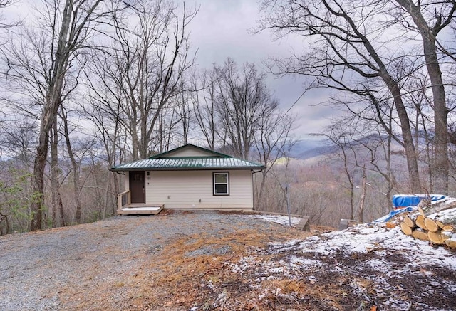 view of snowy exterior featuring a standing seam roof, metal roof, and a forest view