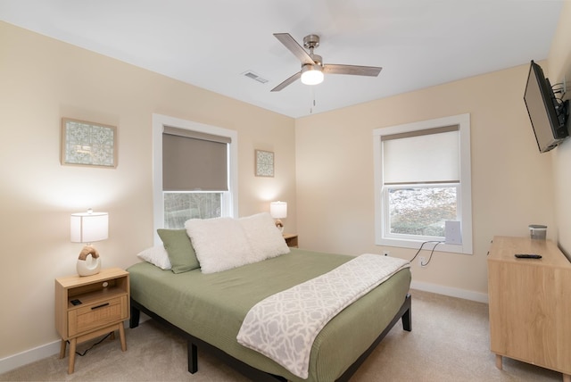 bedroom with visible vents, light colored carpet, baseboards, and a ceiling fan