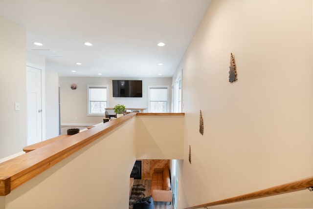corridor featuring baseboards, an upstairs landing, and recessed lighting