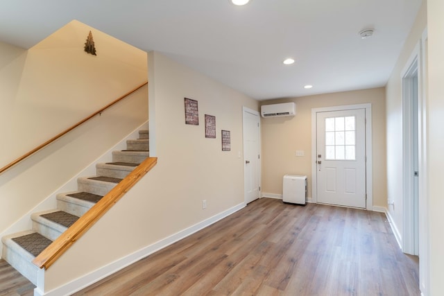 foyer with an AC wall unit, baseboards, recessed lighting, stairway, and wood finished floors
