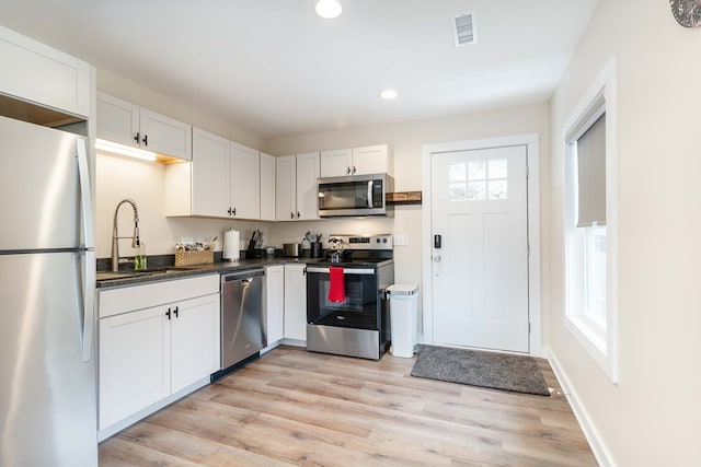 kitchen with recessed lighting, dark countertops, visible vents, stainless steel appliances, and a sink