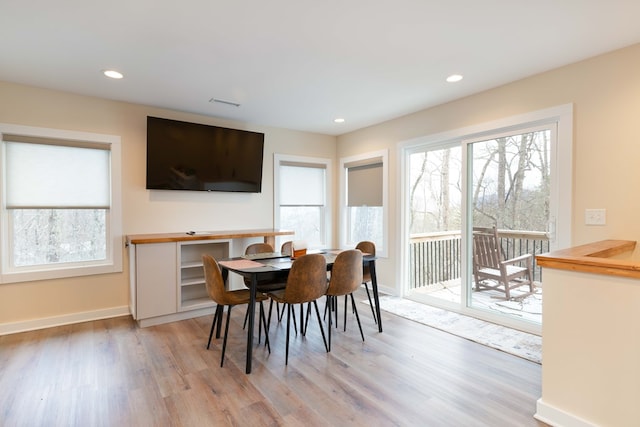 dining room with baseboards, light wood finished floors, recessed lighting, and a healthy amount of sunlight