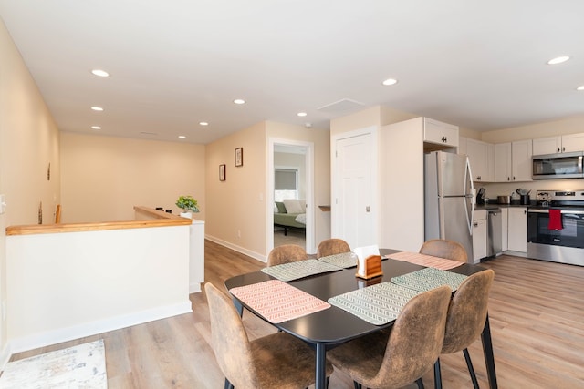 dining room with light wood-style flooring, recessed lighting, and baseboards