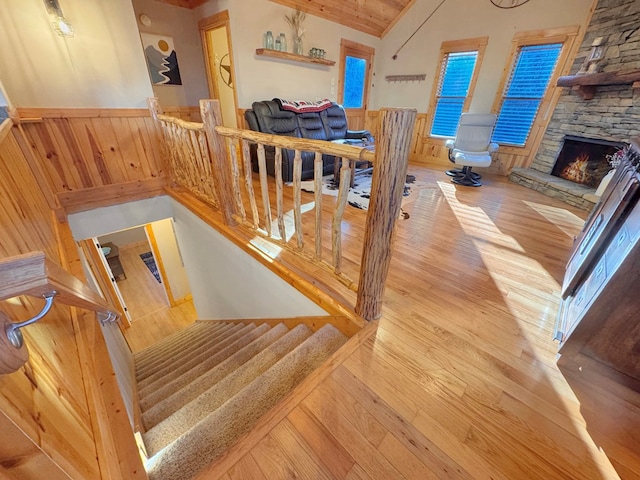 stairway featuring a fireplace, vaulted ceiling, wood finished floors, and a wainscoted wall