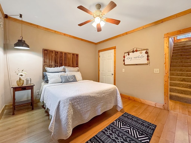 bedroom featuring light wood-style flooring, a ceiling fan, baseboards, and ornamental molding