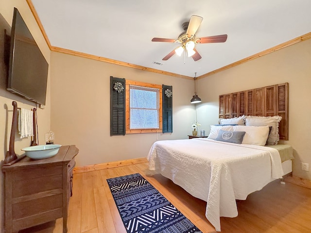 bedroom with baseboards, visible vents, ceiling fan, crown molding, and light wood-type flooring