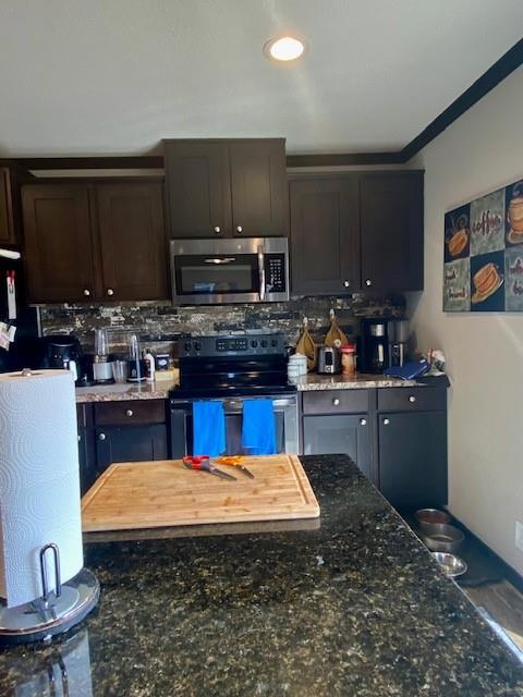 kitchen featuring dark stone countertops, dark brown cabinetry, appliances with stainless steel finishes, and tasteful backsplash