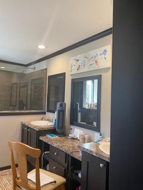 bathroom featuring vanity, ornamental molding, and tiled shower