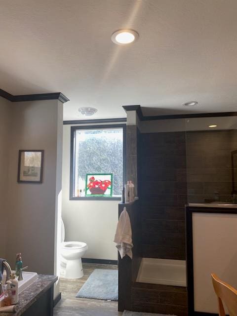 bathroom featuring toilet, crown molding, hardwood / wood-style floors, and walk in shower