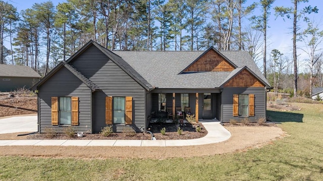 view of front of home featuring a shingled roof, a front yard, and a porch