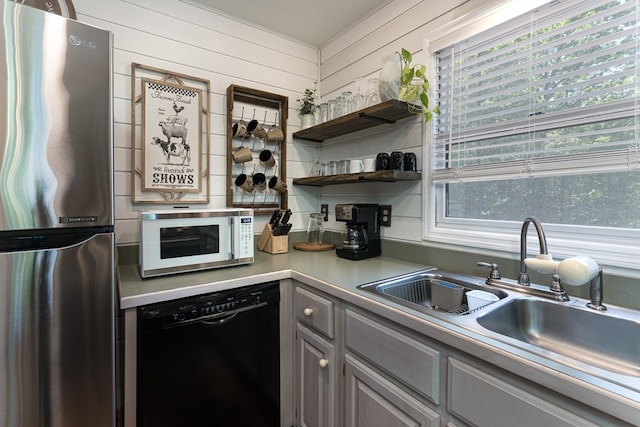 kitchen with dishwasher, wooden walls, sink, and stainless steel fridge