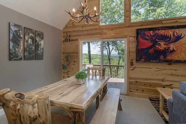 dining area featuring high vaulted ceiling, wood walls, and an inviting chandelier