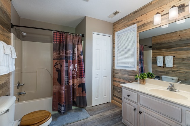 full bathroom featuring toilet, hardwood / wood-style flooring, wooden walls, vanity, and shower / tub combo