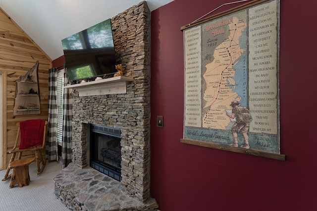 living room featuring wooden walls, lofted ceiling, and a fireplace