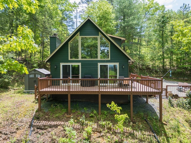 rear view of property with a wooden deck and a storage shed