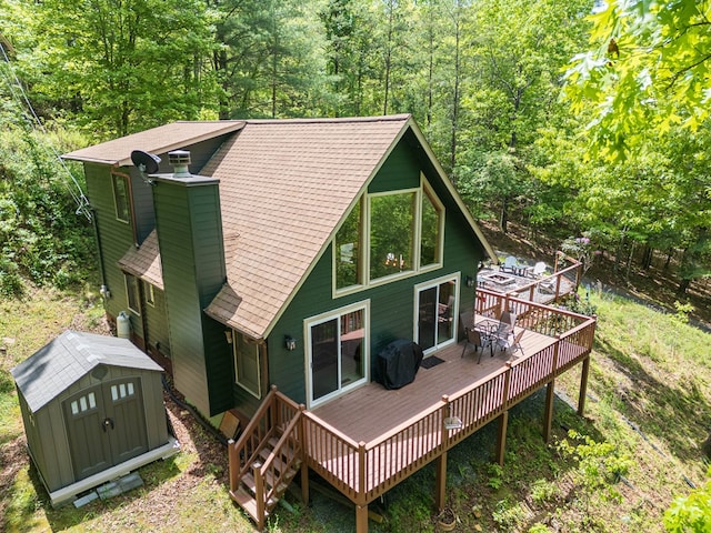 back of property with a wooden deck and a storage shed