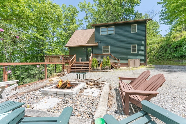 rear view of house with a wooden deck and an outdoor fire pit