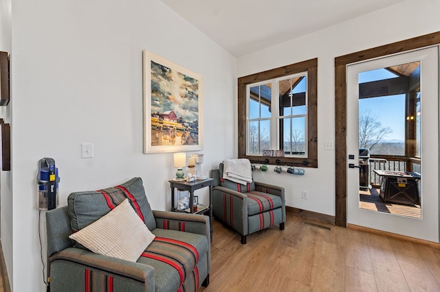 living area with visible vents, light wood-type flooring, a wealth of natural light, and baseboards