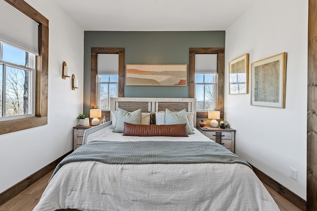 bedroom featuring multiple windows, baseboards, and dark wood-style flooring