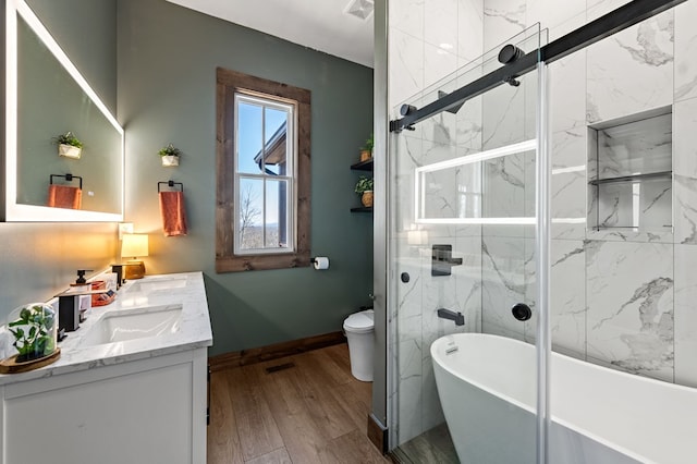 full bath with vanity, wood finished floors, a marble finish shower, a soaking tub, and toilet