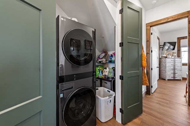 laundry room featuring light wood finished floors, laundry area, and stacked washing maching and dryer