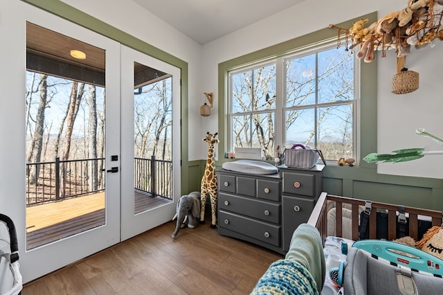 interior space featuring wood finished floors, a decorative wall, french doors, and a wainscoted wall