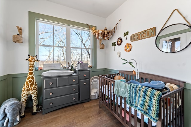 bedroom featuring wood finished floors, a wainscoted wall, and a sink