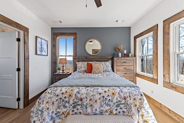 bedroom with visible vents, baseboards, ceiling fan, and wood finished floors