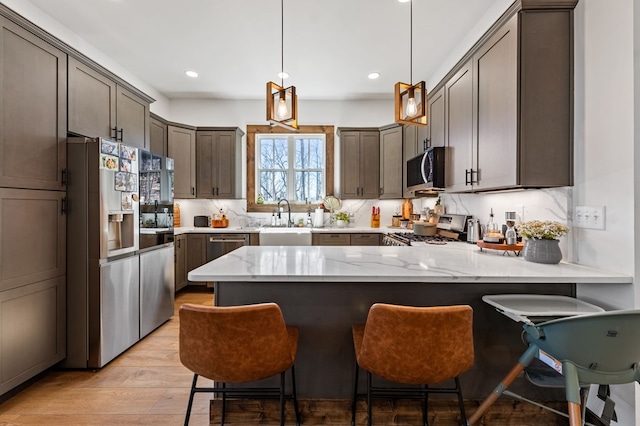 kitchen featuring backsplash, light stone counters, a peninsula, stainless steel appliances, and a sink