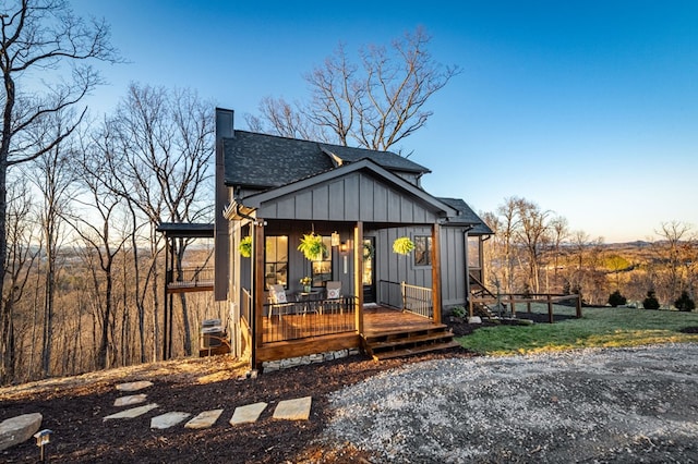 view of front of property featuring board and batten siding, a chimney, a front yard, and a shingled roof