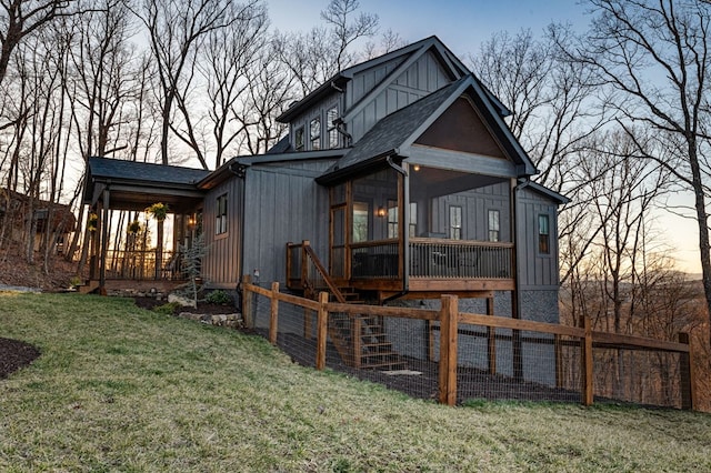 back of house featuring board and batten siding, a yard, and roof with shingles