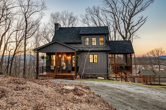 view of front of home with fence, covered porch, a shingled roof, a chimney, and board and batten siding