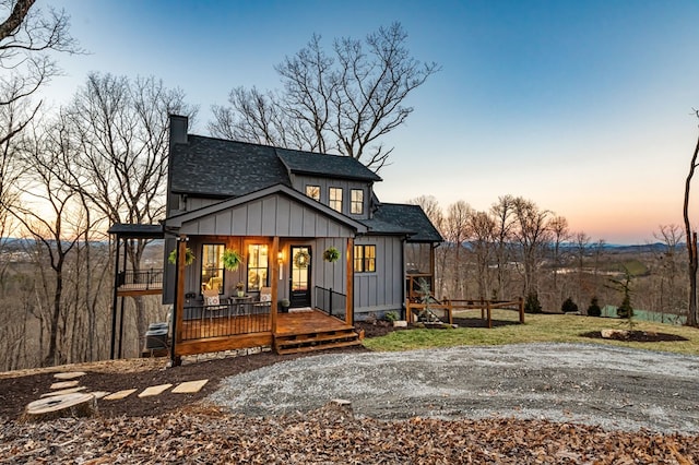 view of front of property featuring a porch, board and batten siding, a chimney, and a shingled roof