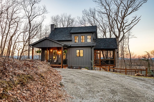 view of front of property with fence, roof with shingles, covered porch, a chimney, and board and batten siding