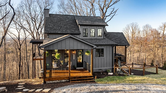 exterior space featuring board and batten siding, a chimney, and a shingled roof