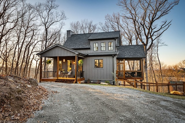 view of front of home with driveway, a porch, fence, roof with shingles, and a chimney