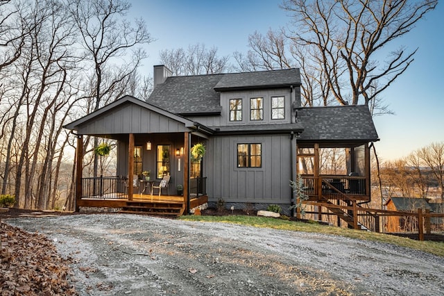 modern inspired farmhouse featuring covered porch, board and batten siding, a chimney, and a shingled roof