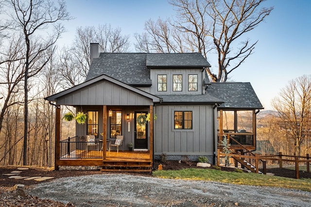 view of front facade with a chimney, a porch, board and batten siding, a shingled roof, and stairs