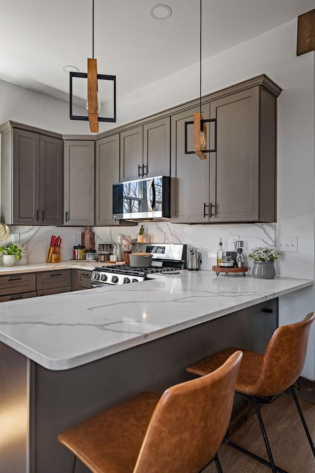 kitchen with light stone counters, a peninsula, stainless steel appliances, a kitchen bar, and tasteful backsplash