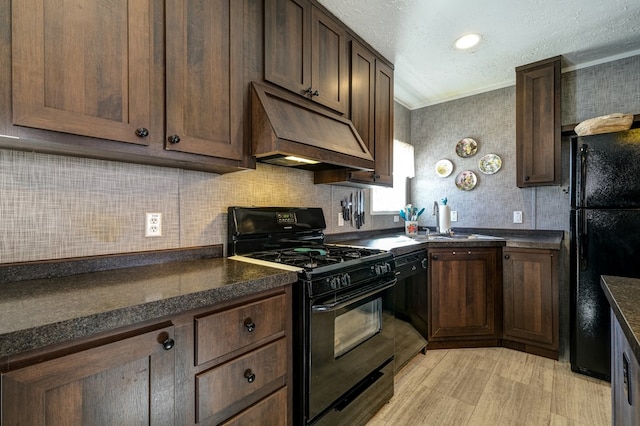 kitchen featuring dark brown cabinetry, sink, black appliances, and custom range hood