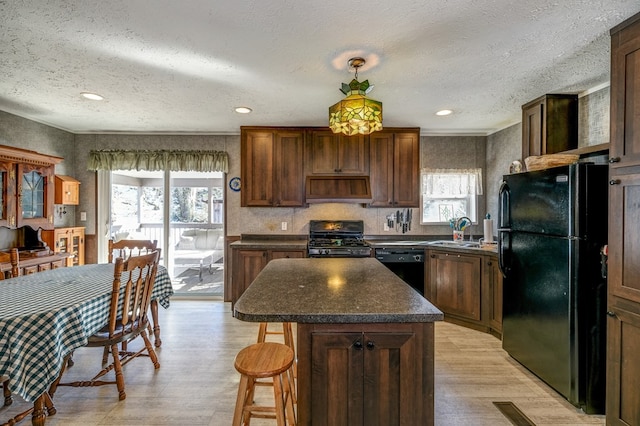 kitchen featuring a breakfast bar, sink, a center island, range hood, and black appliances