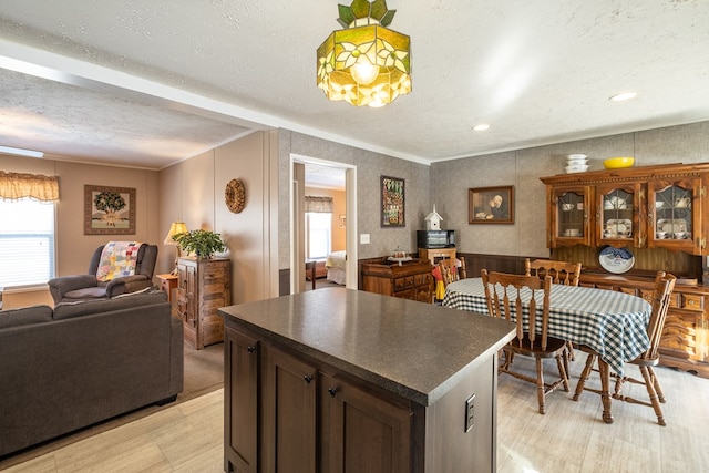 kitchen featuring crown molding, light hardwood / wood-style floors, a textured ceiling, and a kitchen island