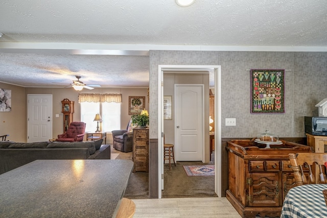 carpeted living room featuring ceiling fan and a textured ceiling