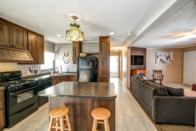 kitchen featuring premium range hood, a kitchen island, a breakfast bar, sink, and black appliances