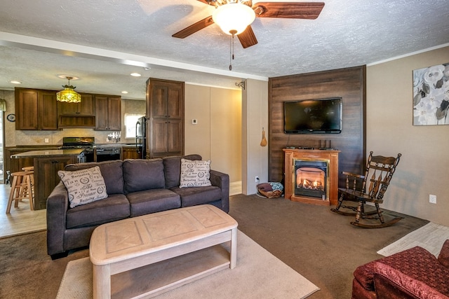 living room featuring ceiling fan, sink, a textured ceiling, and carpet flooring