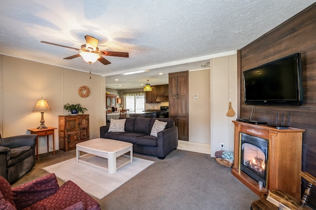 living room featuring ceiling fan, crown molding, light colored carpet, and a textured ceiling