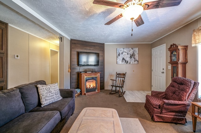 carpeted living room featuring ceiling fan, ornamental molding, a large fireplace, and a textured ceiling