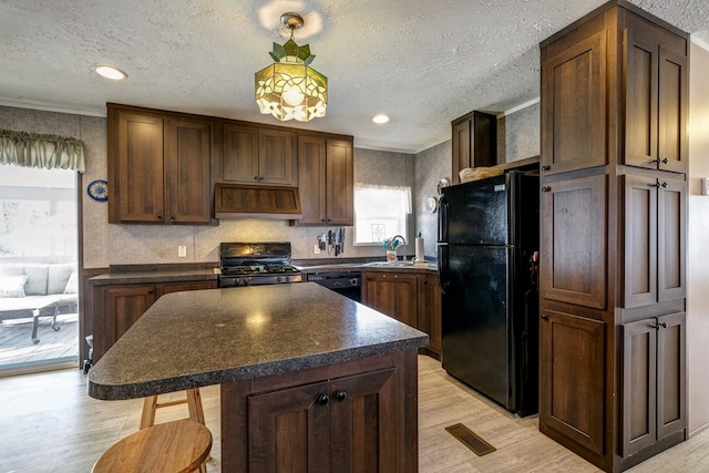 kitchen featuring ornamental molding, light hardwood / wood-style floors, a kitchen island, and black appliances